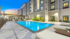 Un hôtel moderne doté d’une piscine, d’un espace extérieur aménagé et d’une façade bien éclairée.