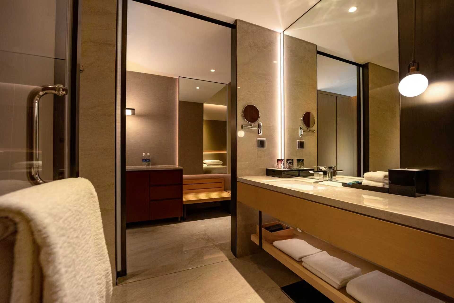 Un baño moderno con un espejo grande, un tocador con lavabo y una zona de ducha.