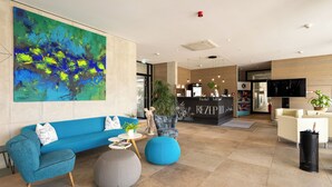 Eine moderne Lobby mit einem blauen Sofa, einem runden Ottomanen und einem Empfangstresen.