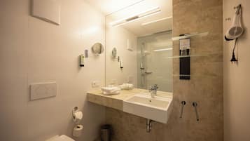 A modern bathroom with a large mirror, two sinks, a toilet, and a shower.