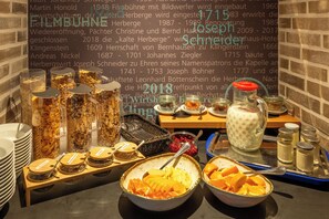 Een ontbijtbuffet met diverse gerechten en een muur met historische informatie.