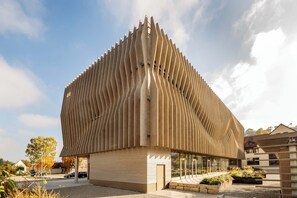 A modern building with a unique ribbed facade and a spacious courtyard.