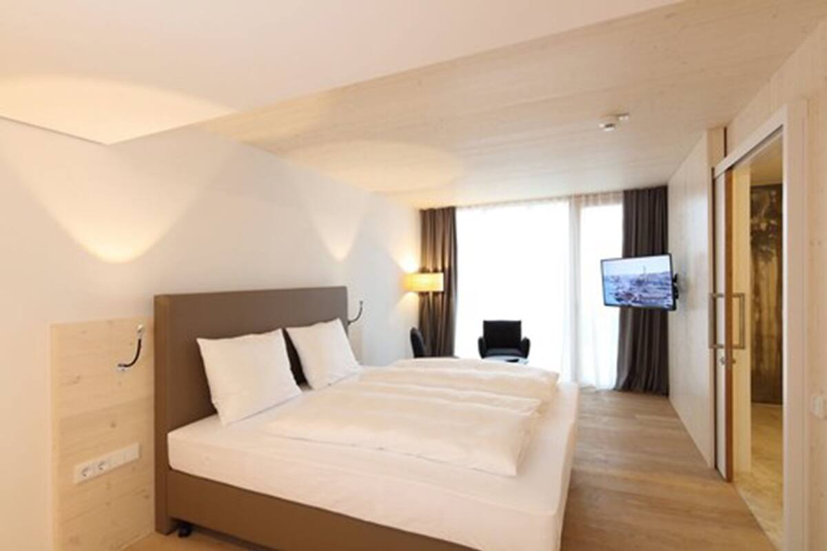 A hotel room with a bed, a television, a desk, and a chair.