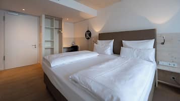 A bedroom with a large bed, a desk, and a wardrobe.