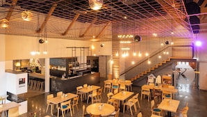 Ein geräumiges Restaurant mit mehreren Tischen, Stühlen, einer Bar und einer Treppe zu einer erhöhten Ebene.