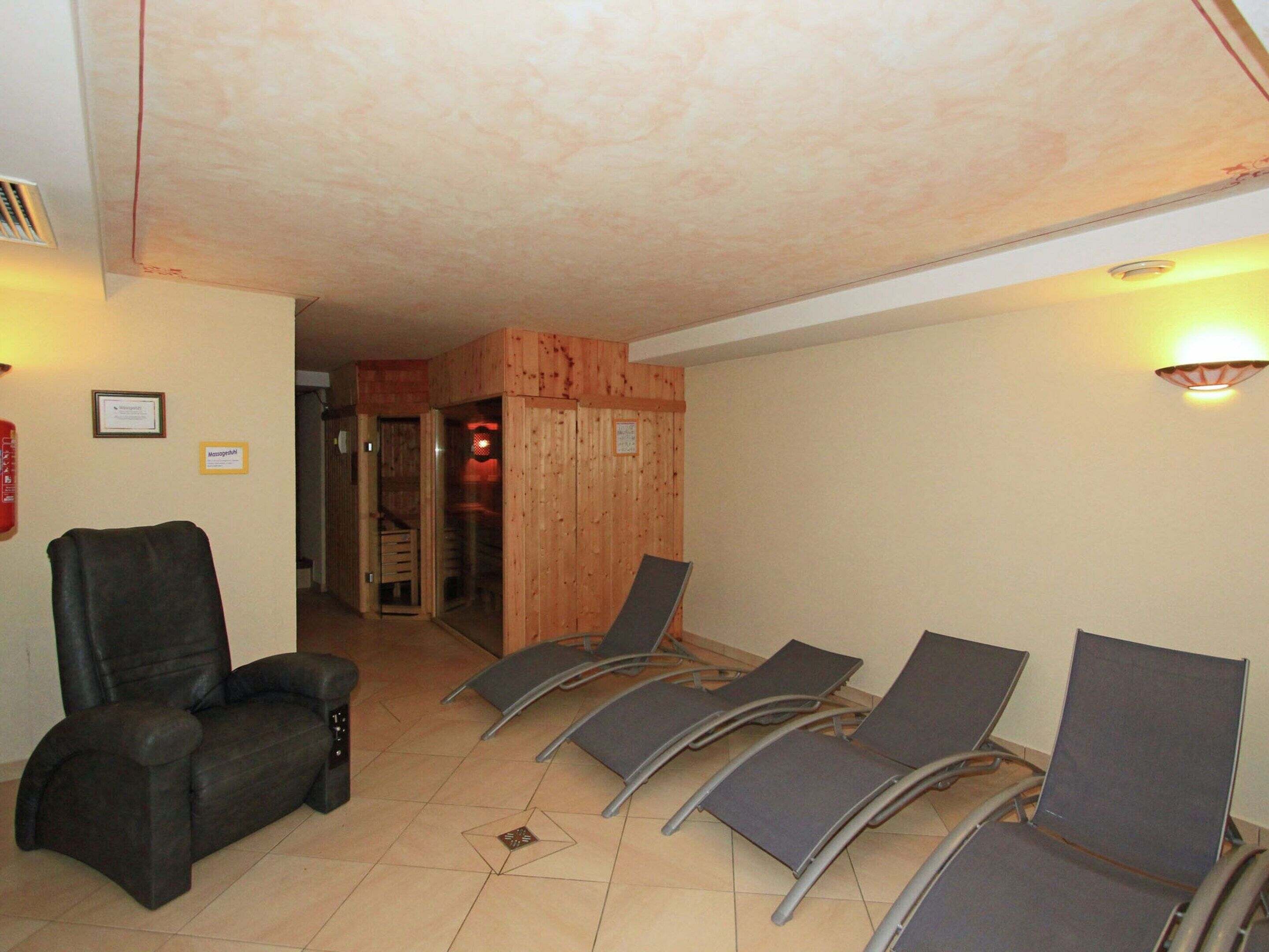 Um quarto com cadeira de massagem, mesa para massagem e quatro cadeiras reclináveis.