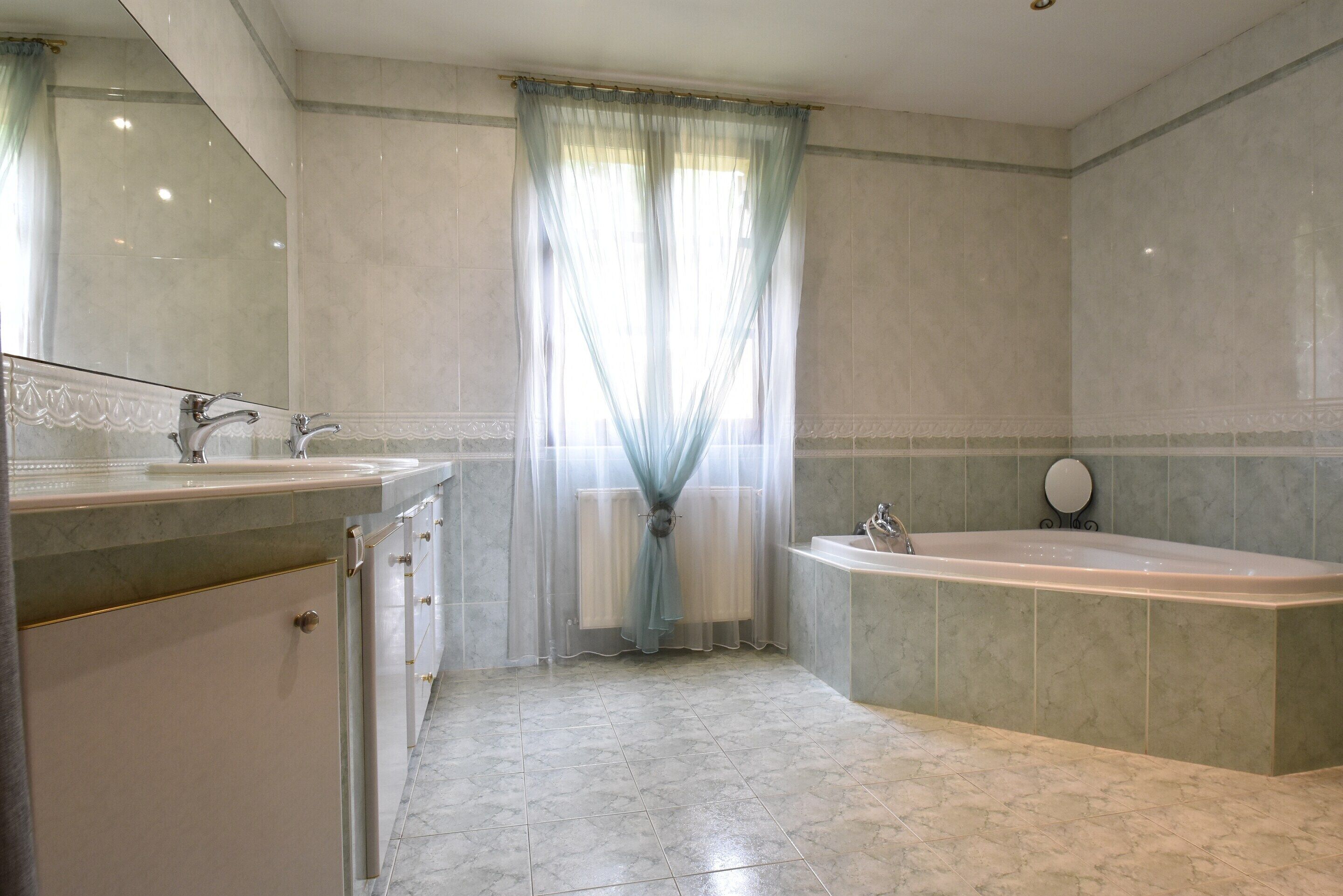 Un baño con bañera, lavabo y espejo.