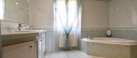 Un baño con bañera, lavabo y espejo.
