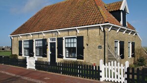 A traditional brick building with a tiled roof, white window frames, and black shutters. - Sleeping in a National Monument is Possible on Texel (Den Hoorn)