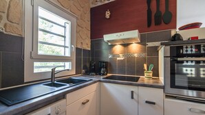 A modern kitchen with a Bosch dishwasher, a window with a view, a coffee maker, and a Brandt oven. - Villa in Pouzols With Private Pool (Pouzols-Minervois)