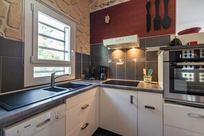 A modern kitchen with a Bosch dishwasher, a window with a view, a coffee maker, and a Brandt oven. - Villa in Pouzols With Private Pool (Pouzols-Minervois)