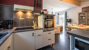 A modern kitchen with a built-in oven, a coffee maker, and a stone accent wall. - Villa in Pouzols With Private Pool (Pouzols-Minervois)