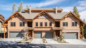 A two-story house with a symmetrical facade, multiple garage doors, and a central chimney.