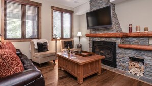 A living room with a fireplace, a television mounted on a stone wall, and a coffee table.
