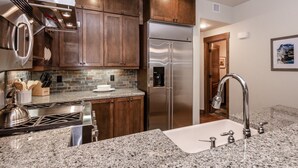 A modern kitchen with granite countertops, stainless steel appliances, and wooden cabinets.
