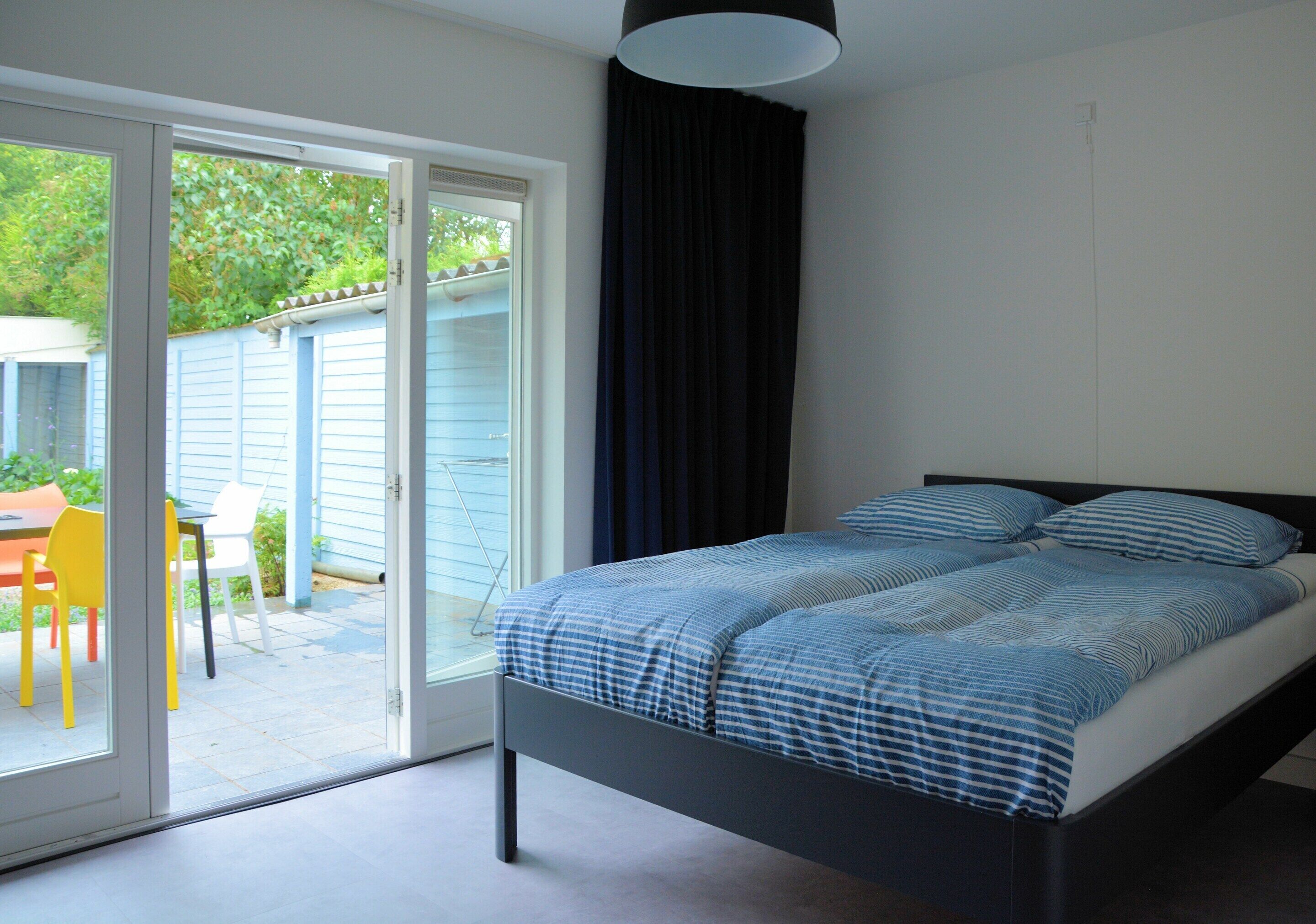 A bedroom with a bed, a sliding glass door to a patio, and a ceiling light.