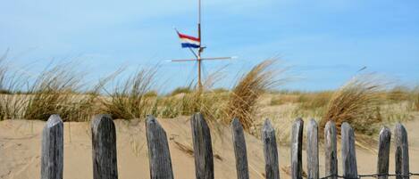 Een houten hek met een vlaggenmast op de achtergrond.