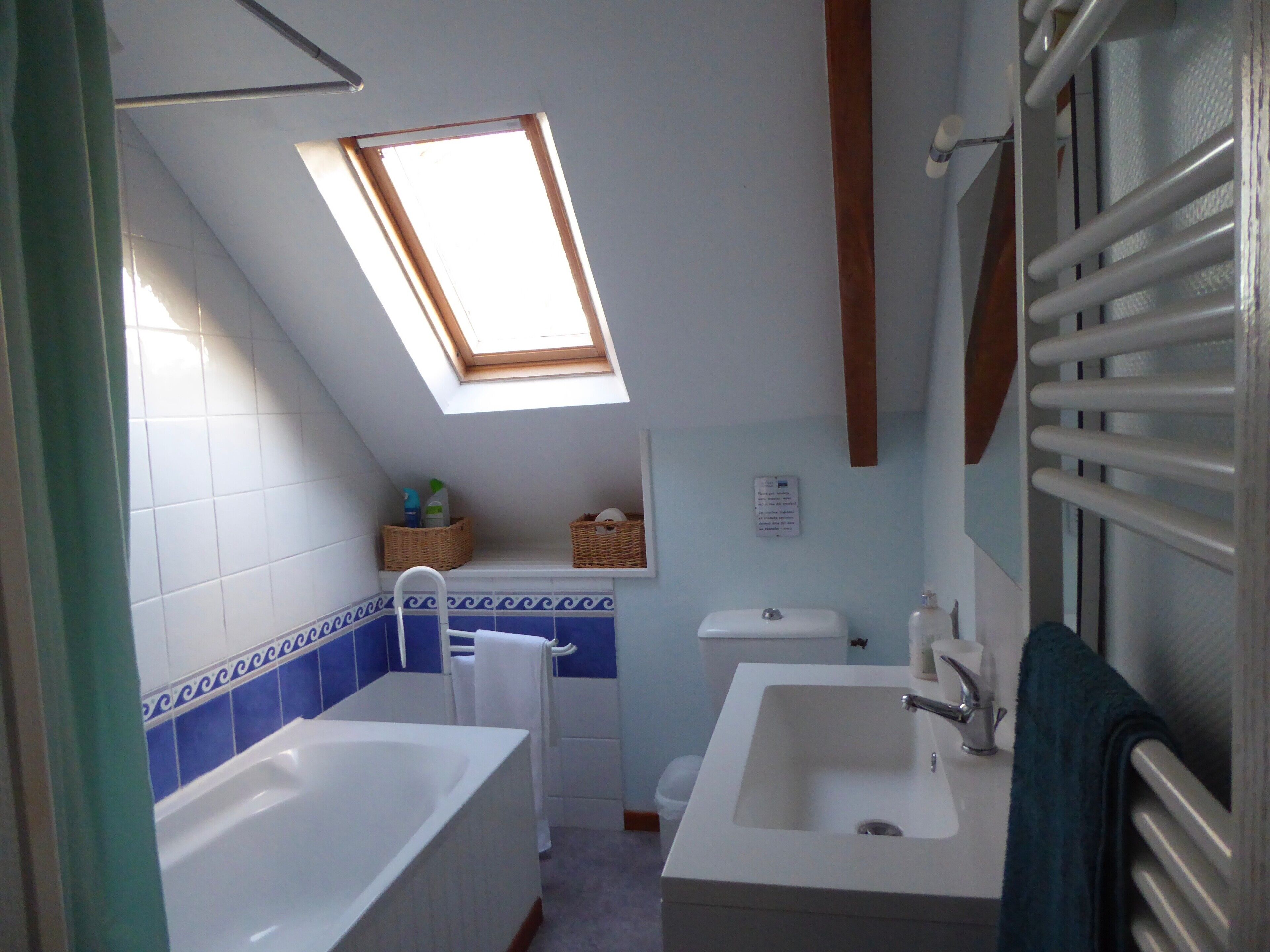 Ein Badezimmer mit Dachfenster, einer Badewanne, einem Waschbecken und einer Toilette.