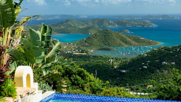 Vista de un paisaje tropical con piscina, abundante vegetación e islas distantes.