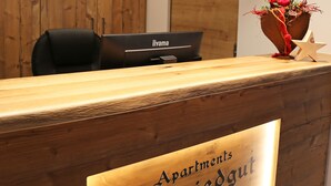A reception desk with a wooden finish, a laptop, and a flower arrangement. - Apartments Schmiedgut (Haus)