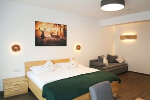 Un dormitorio con cama, mesita de noche, sofá y lámpara de pared.