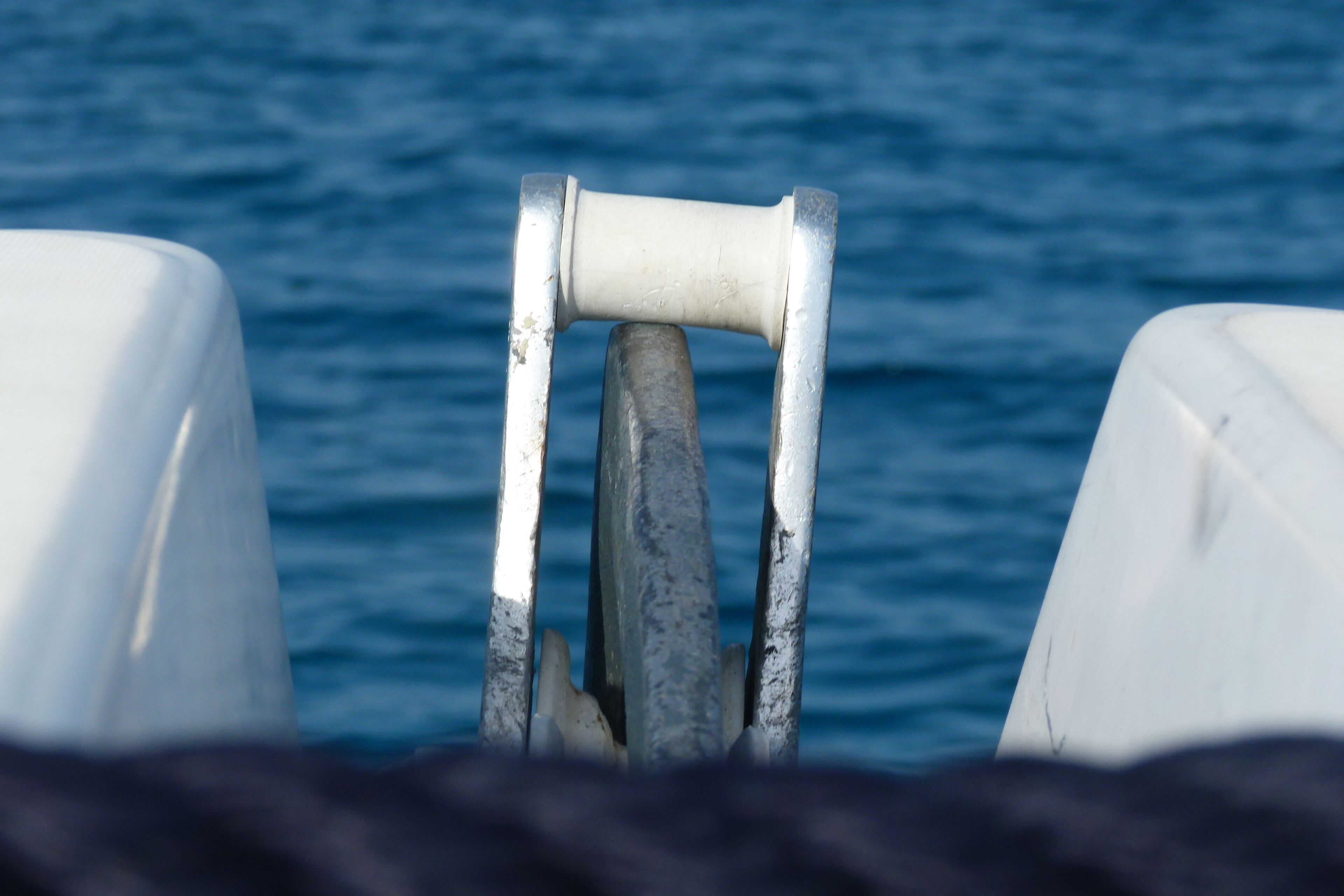 Un gouvernail et une barre de direction de bateau, avec une eau calme en arrière-plan.
