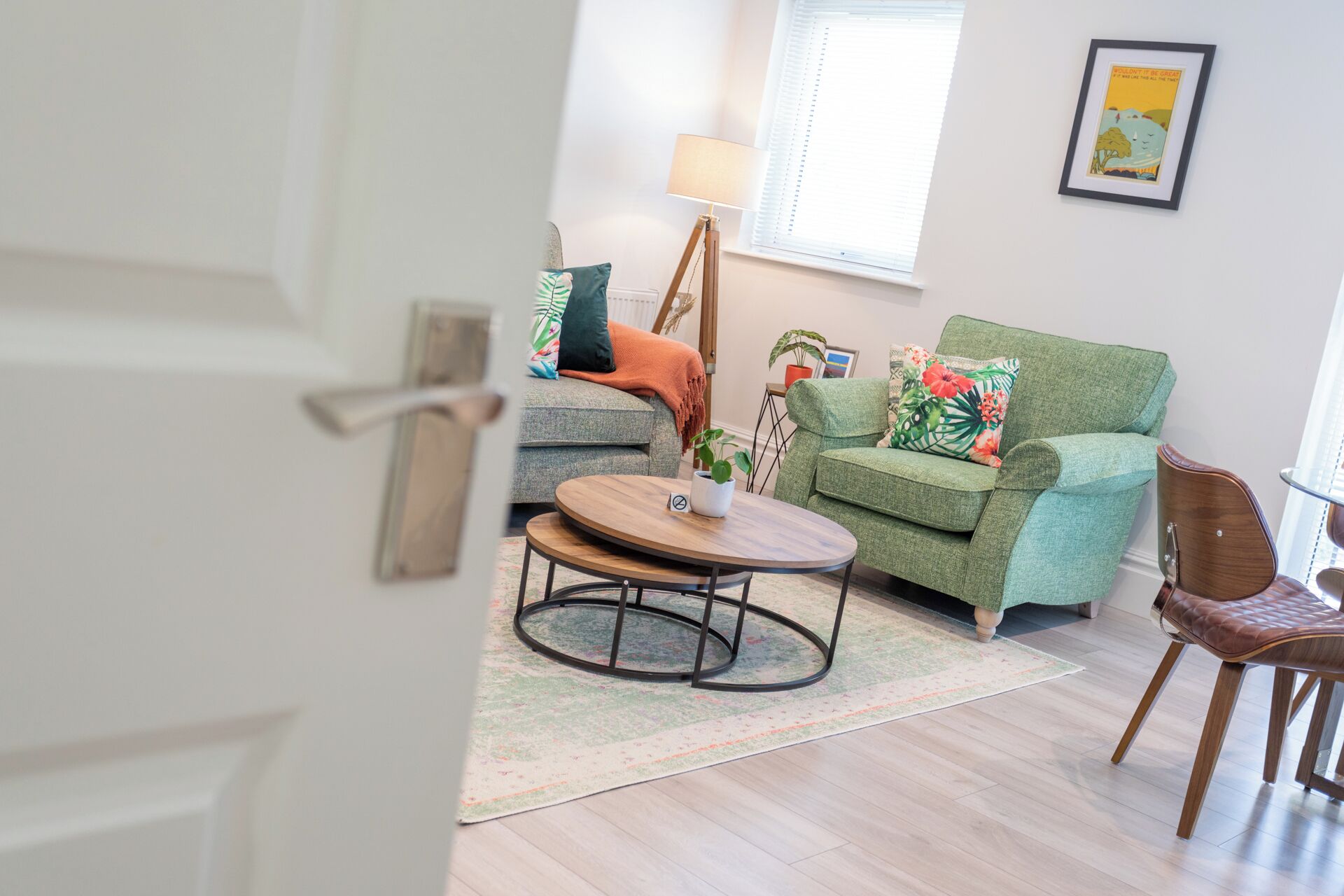 A living room with a green sofa, a wooden coffee table, and a brown leather chair.