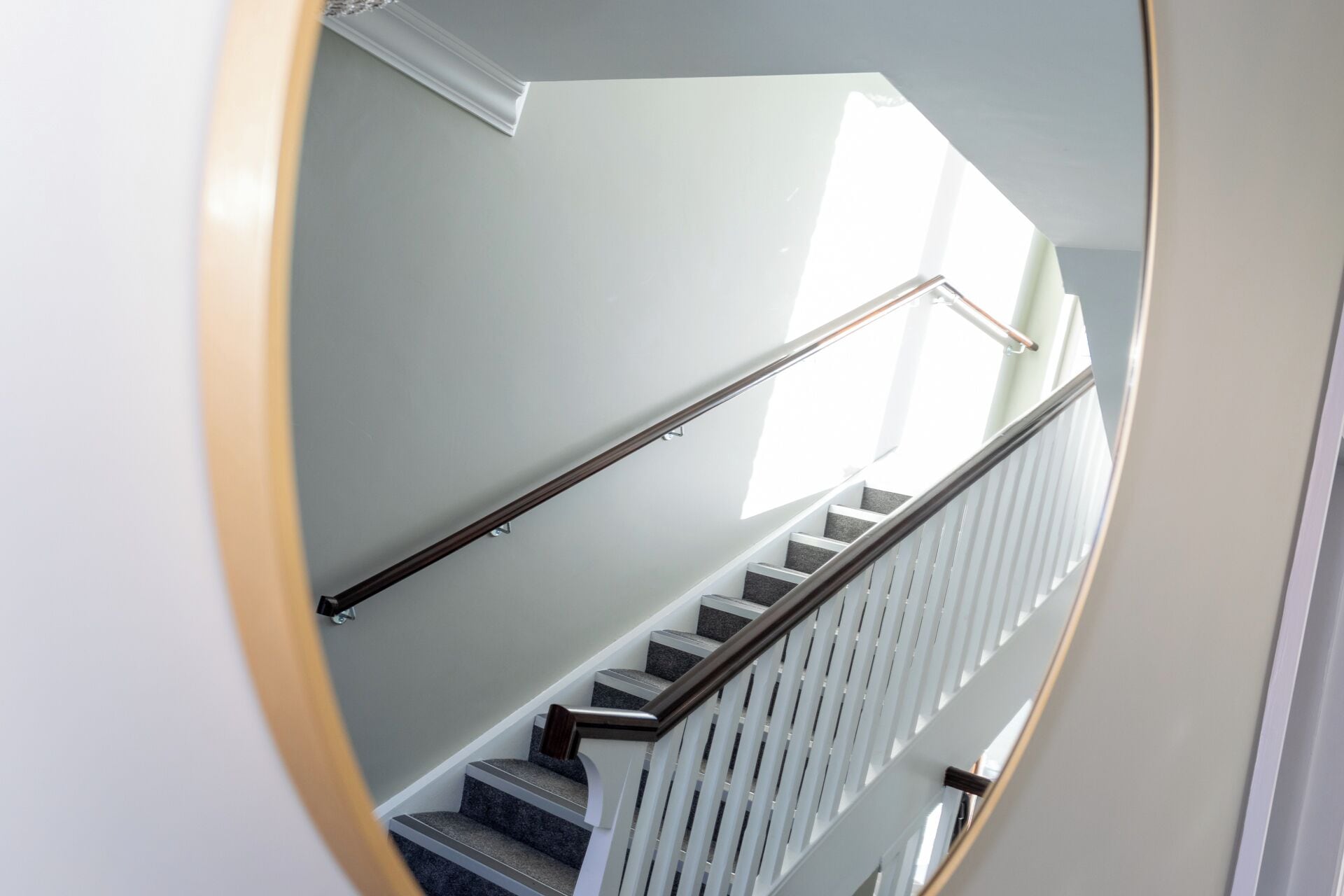 A modern staircase with a handrail, carpeted steps, and a white railing.
