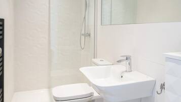 Un baño moderno con ducha, inodoro y lavamanos.
