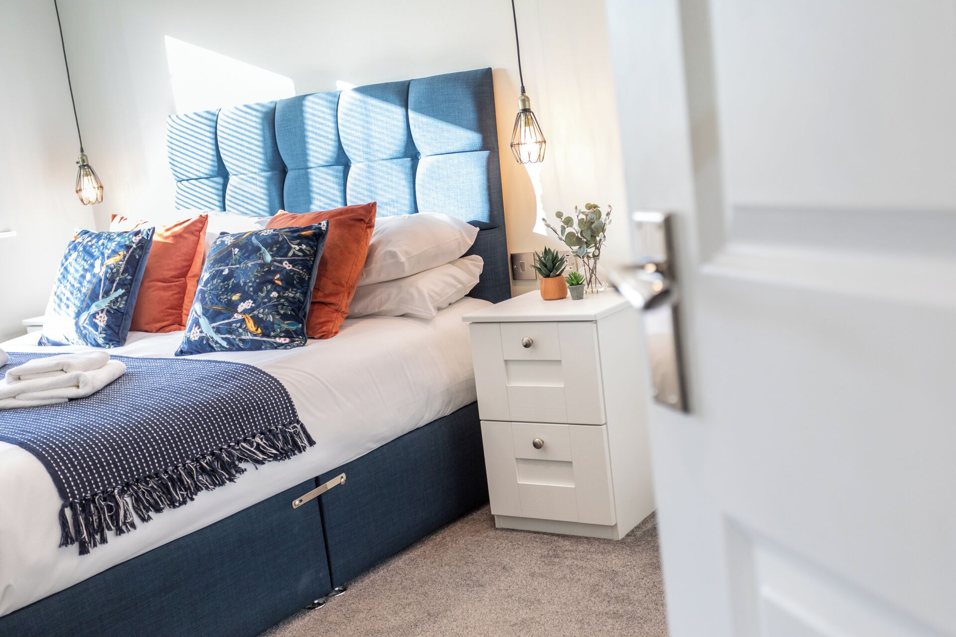 Een keurig opgemaakt slaapkamer met een bed, nachtkastjes en een nachttafeltje.