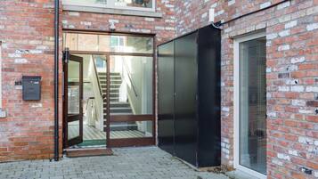 A brick building with a glass door entrance, a staircase, and a black sliding door.