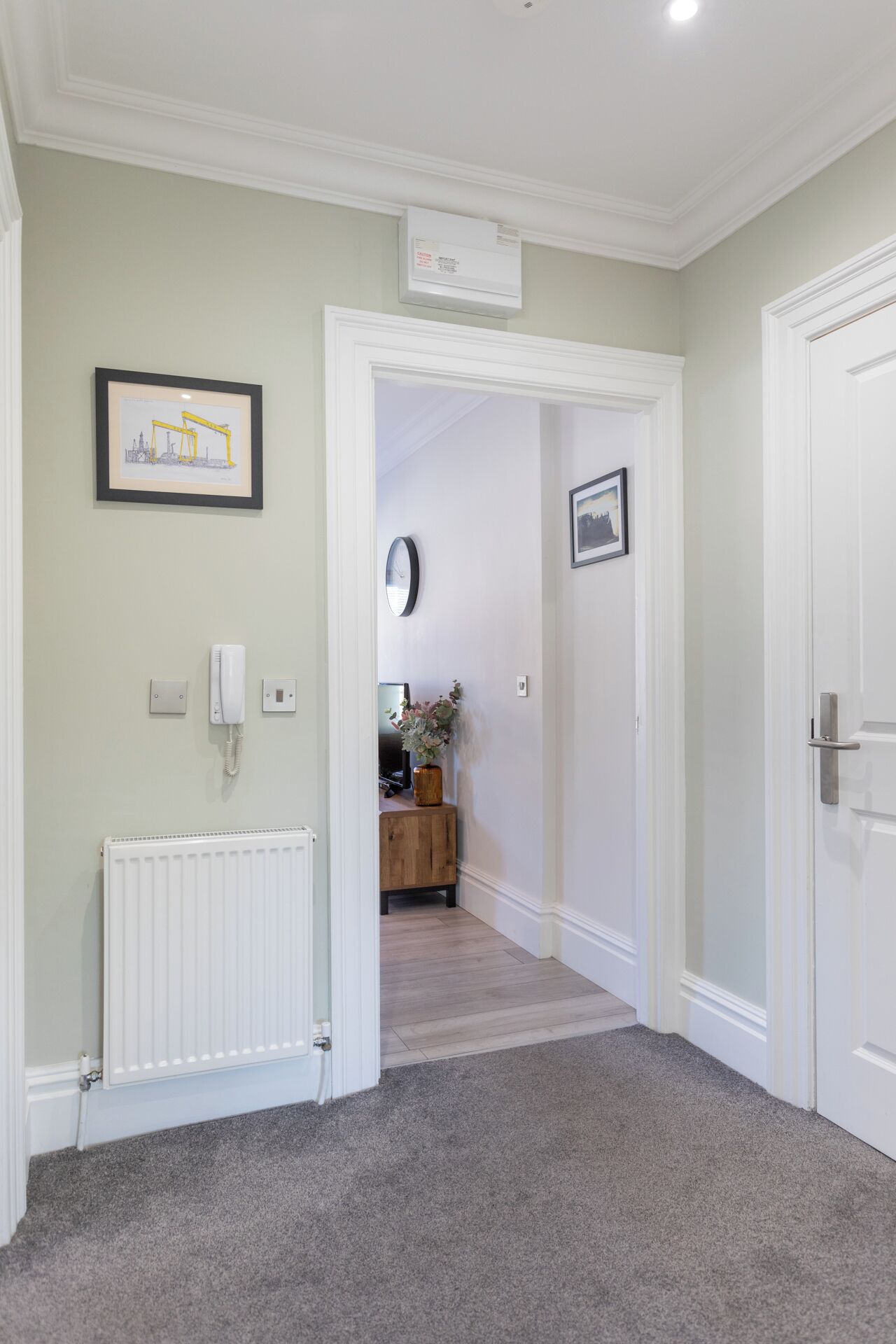 A hallway with a radiator, a framed picture, a phone, and a door.