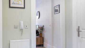 A hallway with a radiator, a framed picture, a phone, and a door.