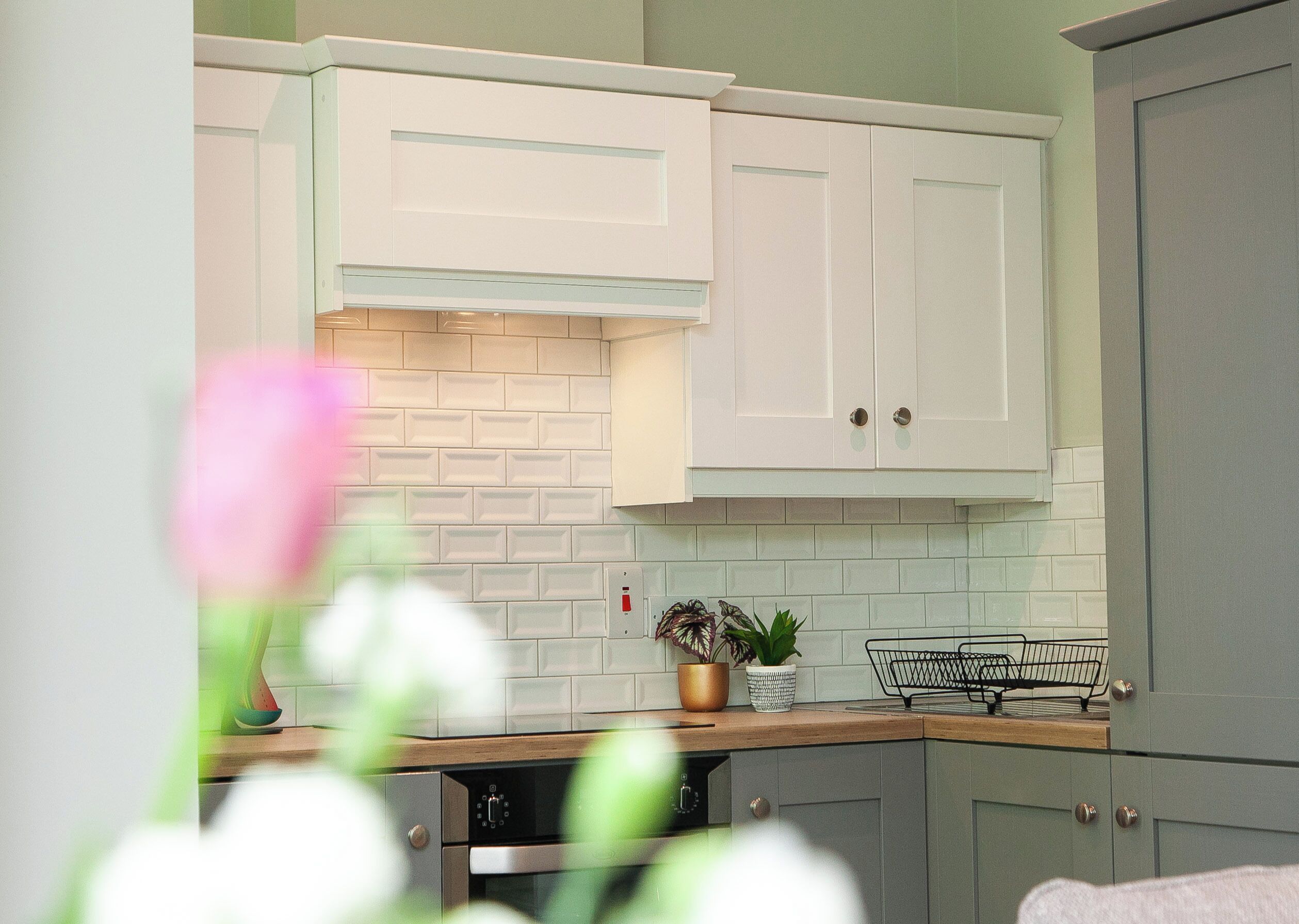 A kitchen with white cabinets, a brick backsplash, and a wooden countertop.