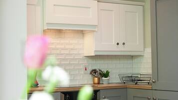 A kitchen with white cabinets, a brick backsplash, and a wooden countertop.