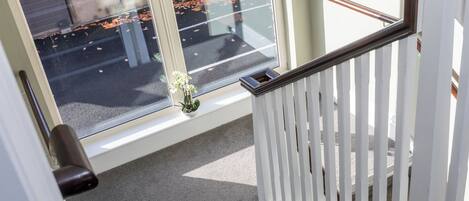 A staircase with a white railing and a potted orchid on the landing.