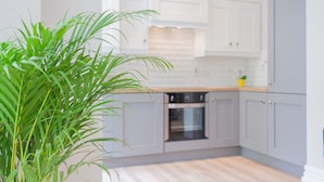 A modern kitchen with grey cabinets, a wooden countertop, and a built-in oven. - The Ulsterville Residences (Belfast)