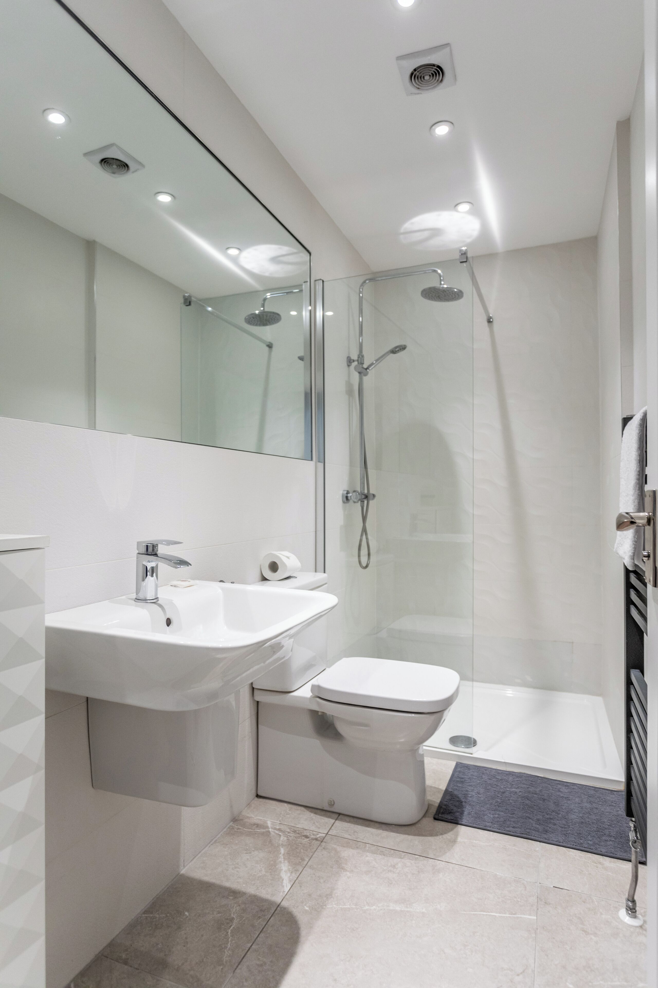 Ein modernes Badezimmer mit einer Duschkabine, einem weißen Waschbecken und einer Toilette.