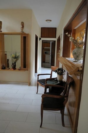Stylish hallway with a wooden bench, mirror, and vase of flowers, leading to a kitchen area.