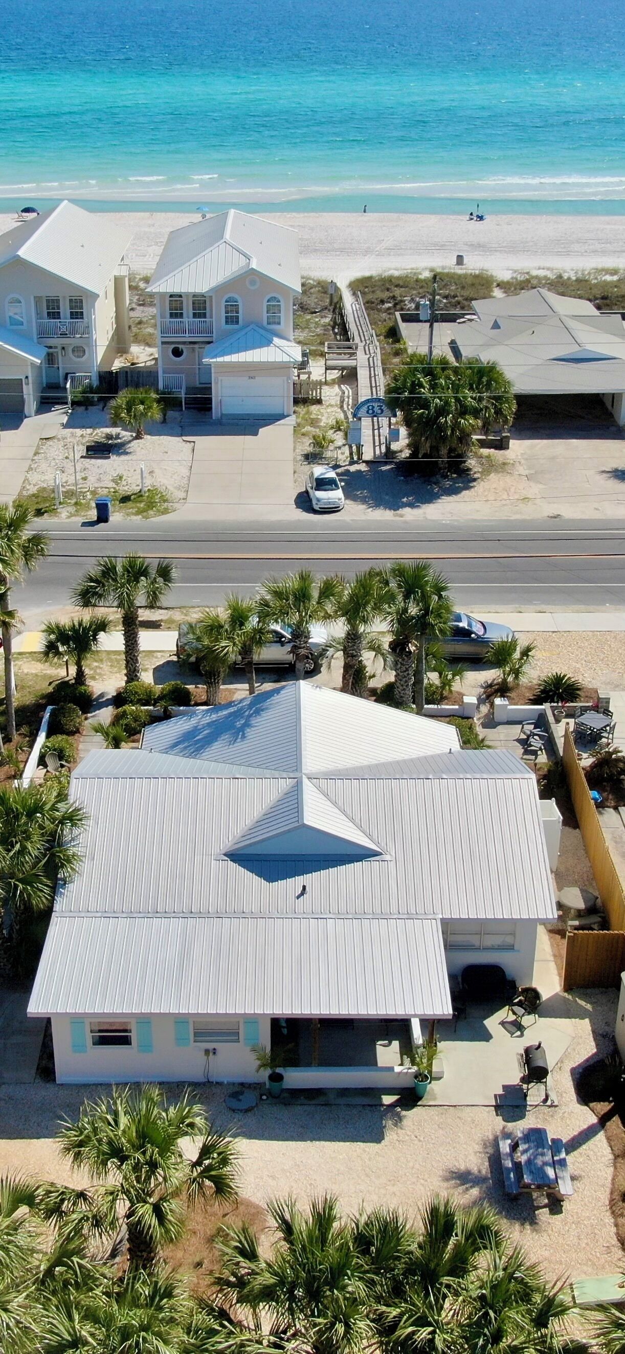 Una propiedad frente a la playa que incluye una casa grande, un garaje y un patio con mobiliario exterior.