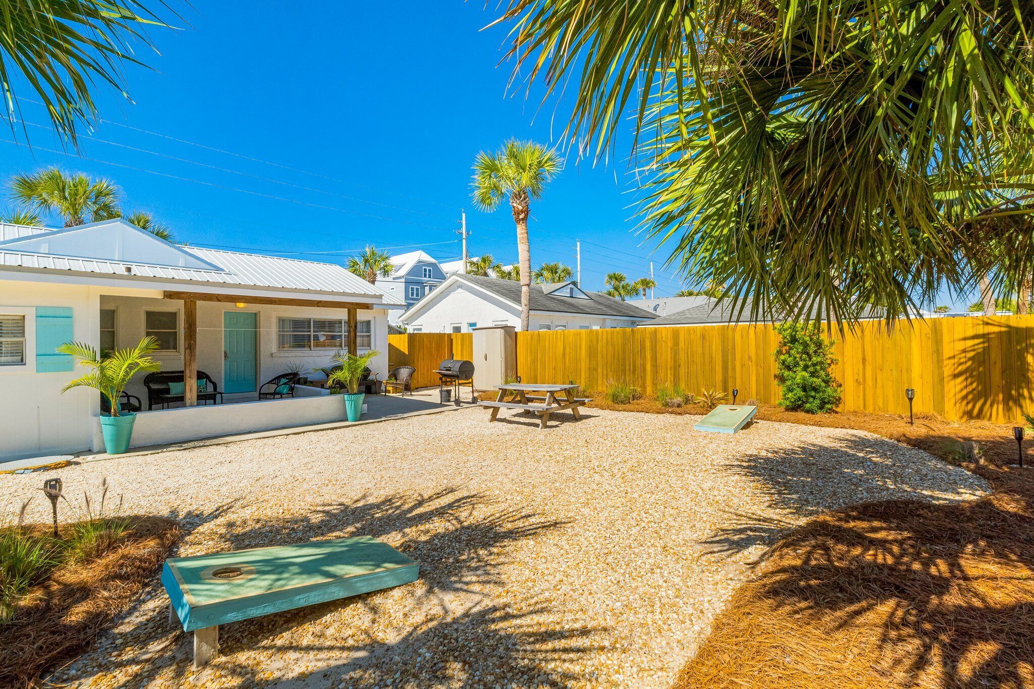 A residential property with a gravel patio, outdoor seating, and a fenced yard.
