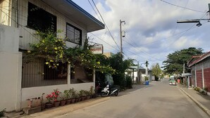 Une rue résidentielle bordée de maisons, avec un scooter garé et une enseigne indiquant « Helardos ».