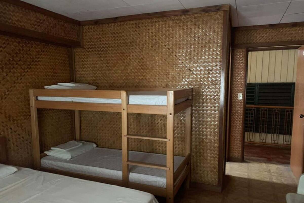 Een slaapkamer met een stapelbed van hout en een enkel bed.