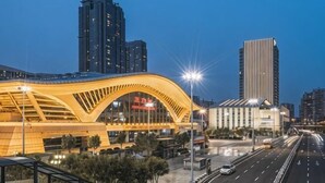 A modern urban bridge with a distinctive arched design, surrounded by high-rise buildings and a well-lit roadway. - Putian Hotel (Xiamen Mingfa Plaza) (Xiamen)