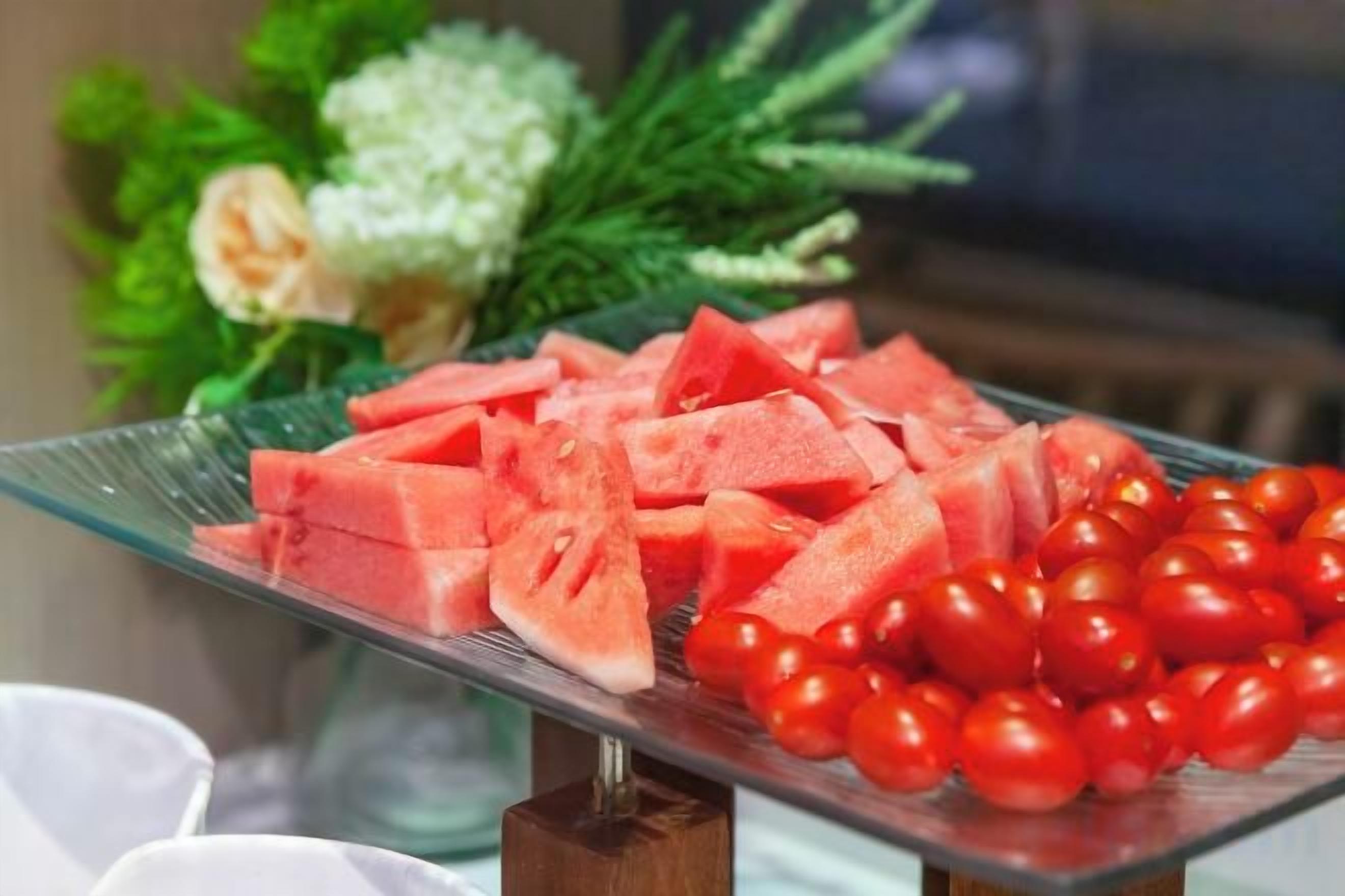 Una placa de vidrio con sandía y tomates cherry.