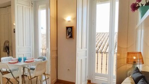 A dining area with a table set for two, a sofa, and a lamp. - Cozy apartment with Beautiful Views (Sevilla)
