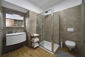 Une salle de bain moderne avec une douche à parois de verre, un lavabo blanc et des toilettes.