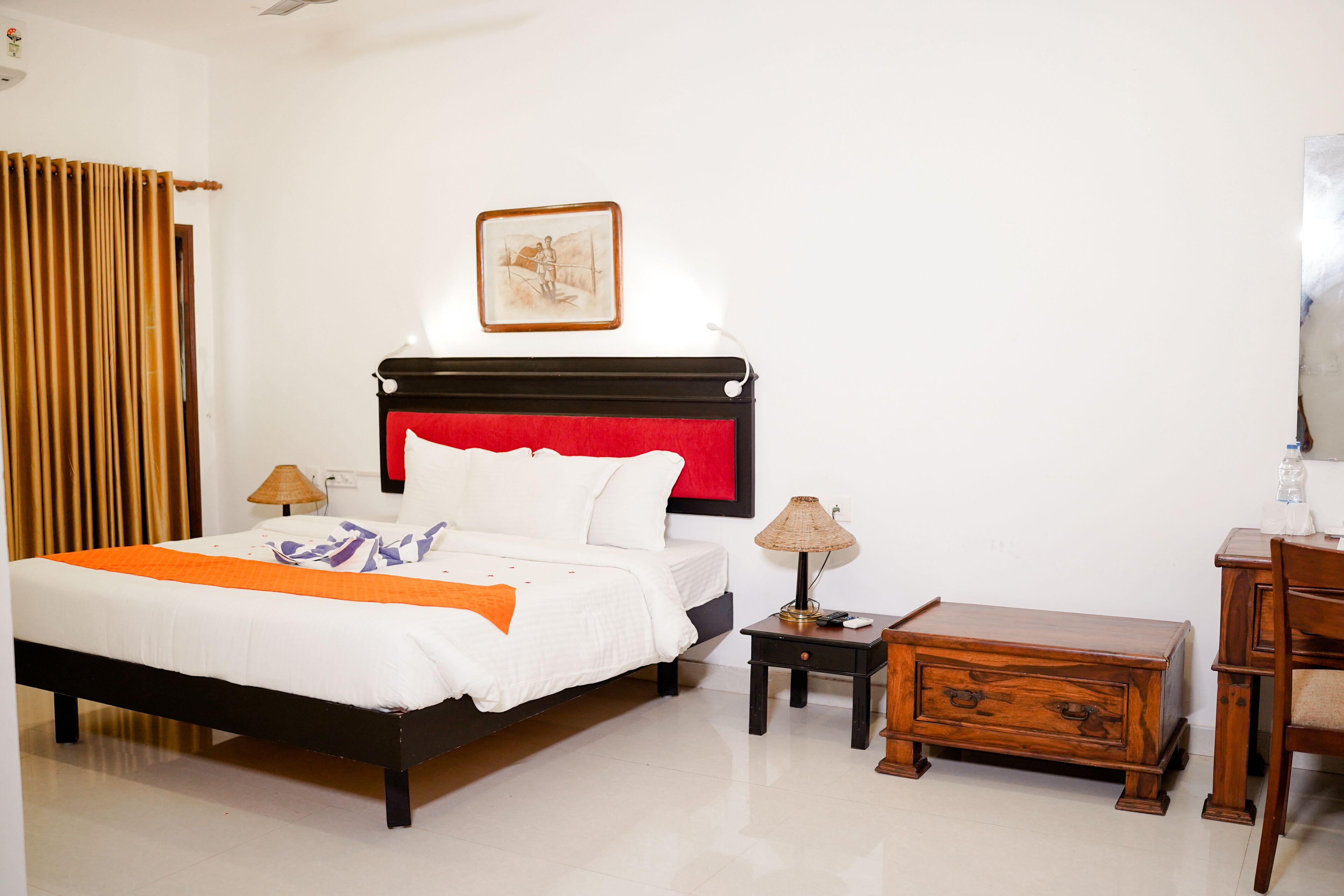 Un dormitorio ordenado con cama, mesitas de noche, una mesita auxiliar de madera y una silla.