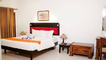 Un dormitorio ordenado con cama, mesitas de noche, una mesita auxiliar de madera y una silla.