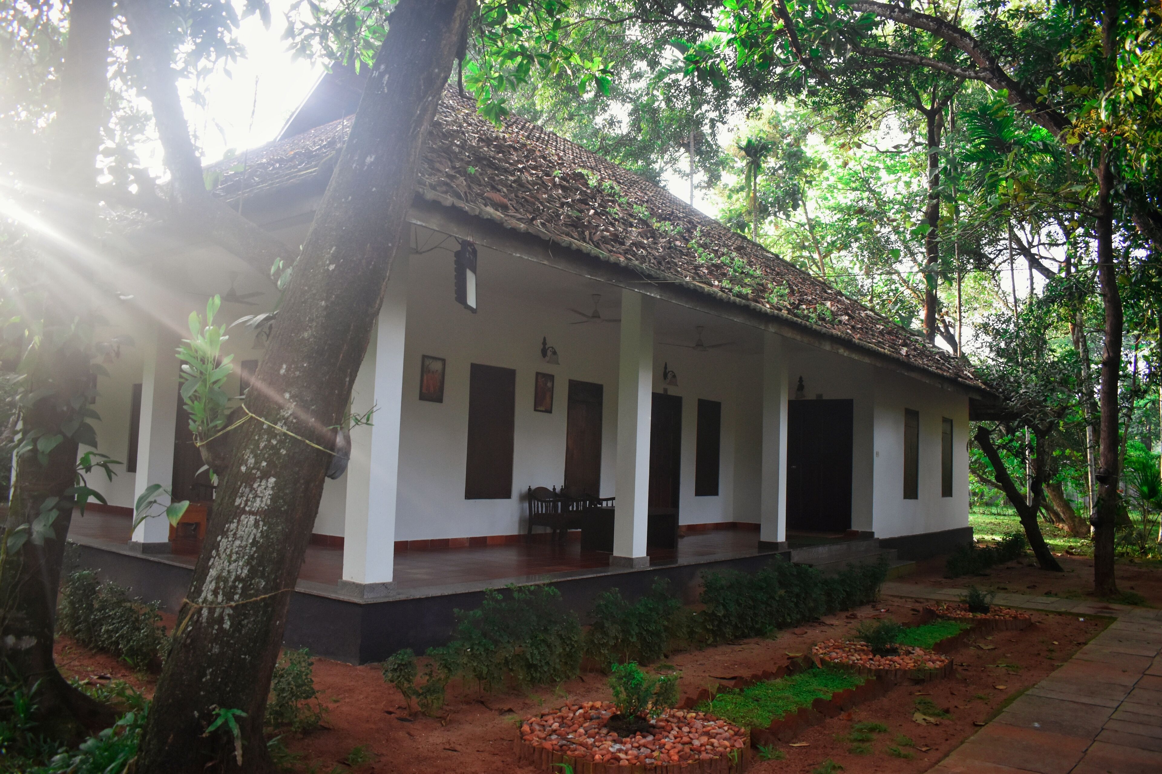 A traditional building with a tiled roof, surrounded by lush greenery and a well-maintained garden.